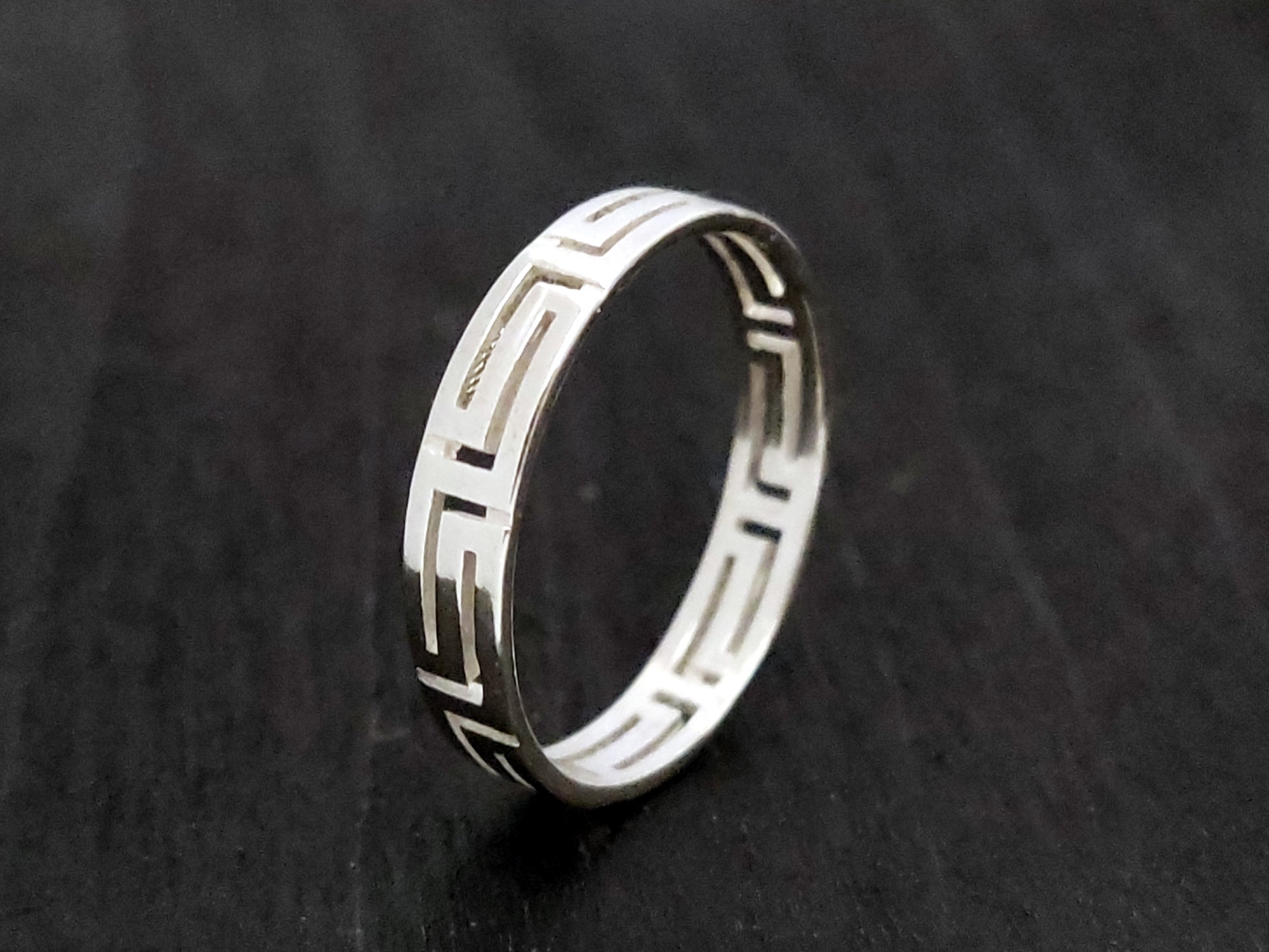 Silver ring with the Greek Key measuring 4mm on black background.