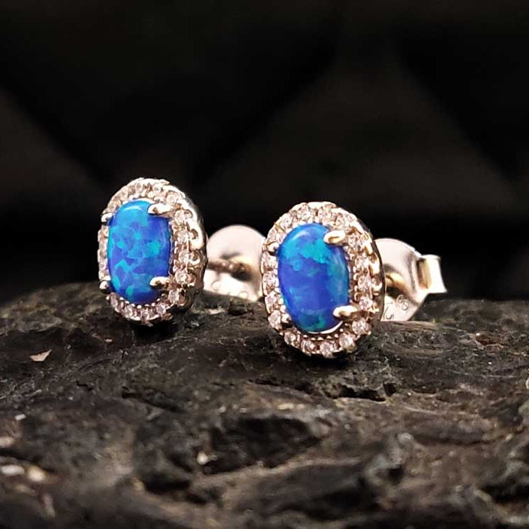 Close-up of sterling silver & blue opal stud earrings – Handcrafted in Greece, shimmering with an iridescent glow.