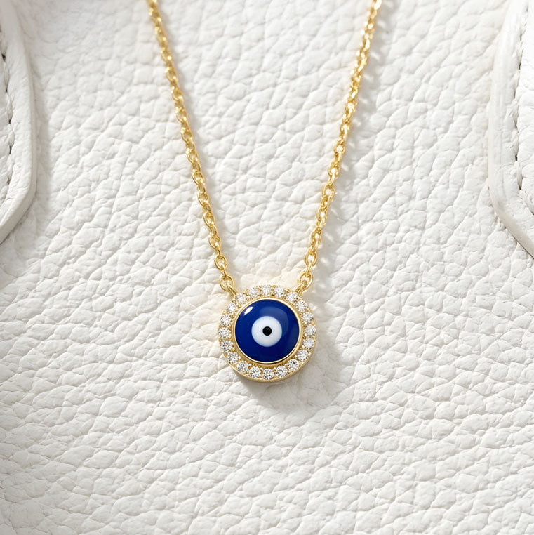 Necklace with a blue evil eye pendant on a white textured background