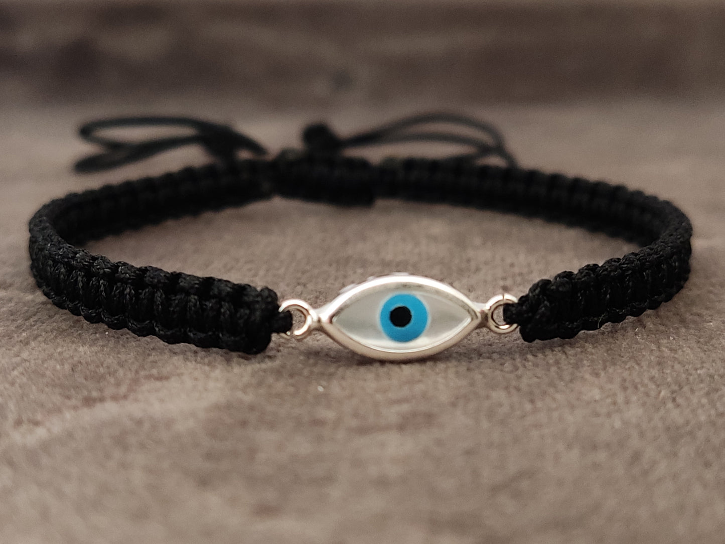 Evil eye silver macrame bracelet on gray velvet.