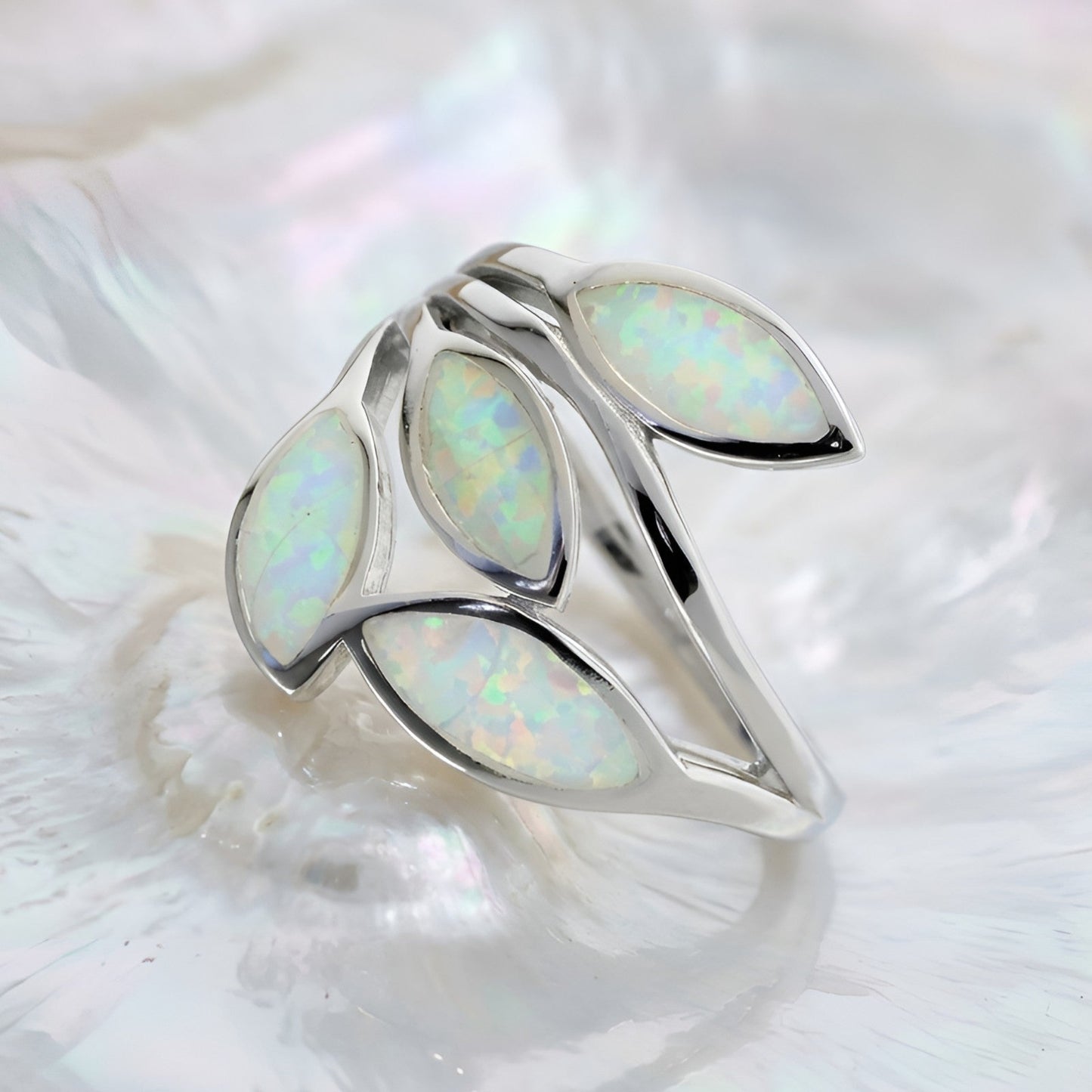 A silver Greek ring featuring five marquise-cut white opal inlays, displayed on a textured white shell.