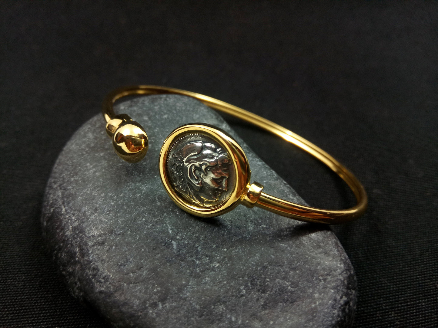Alexander The Great Replica Ancient Greek Coin Sterling Silver Bracelet: A detailed 11mm replica of an ancient Greek coin set in a sterling silver bracelet with a gold-plated 22K finish. Handcrafted in Greece, this bracelet exudes luxury and sophistication, capturing the essence of ancient Greek artistry and heritage.