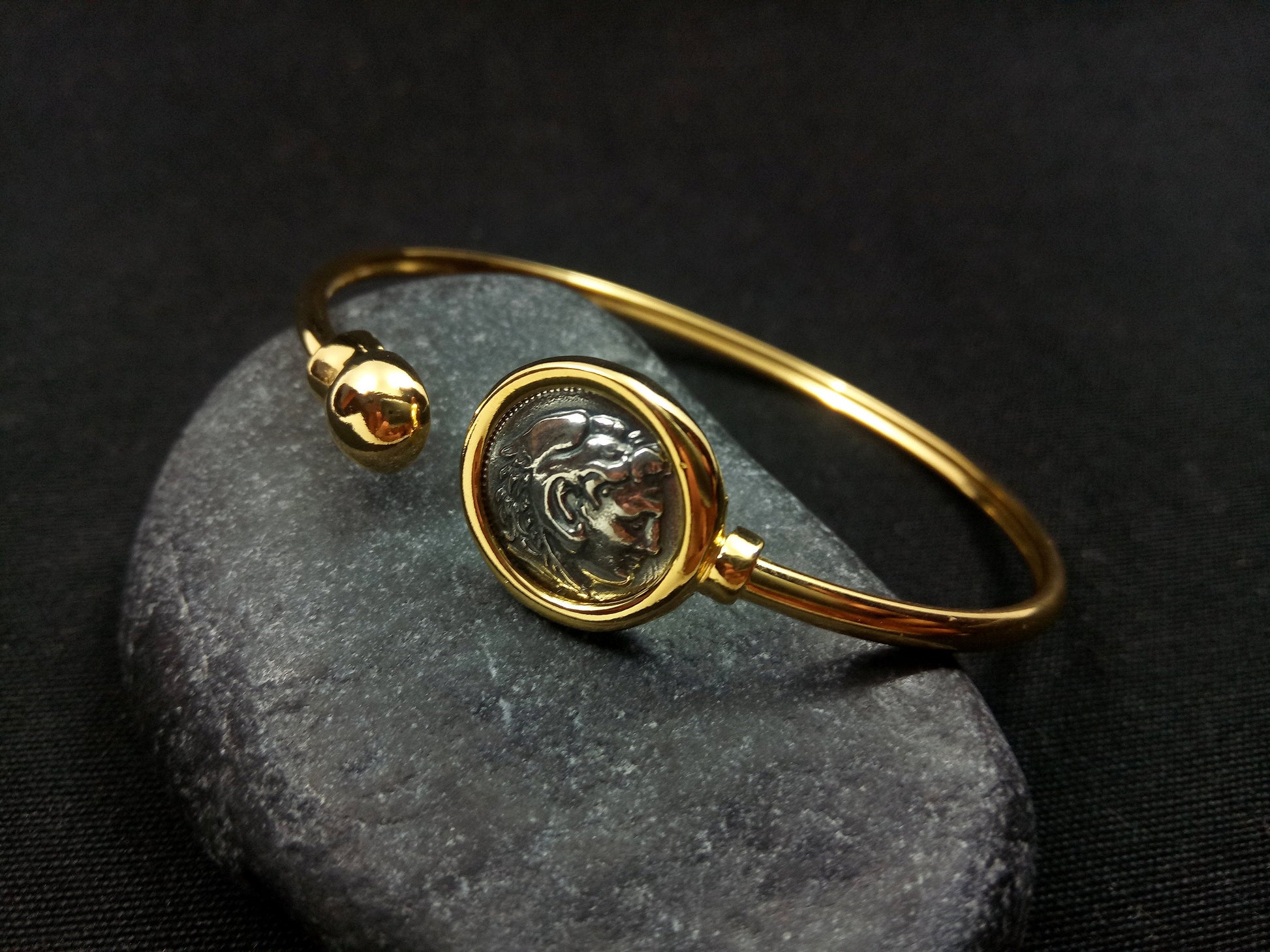 Alexander The Great Replica Ancient Greek Coin Sterling Silver Bracelet: A detailed 11mm replica of an ancient Greek coin set in a sterling silver bracelet with a gold-plated 22K finish. Handcrafted in Greece, this bracelet exudes luxury and sophistication, capturing the essence of ancient Greek artistry and heritage.