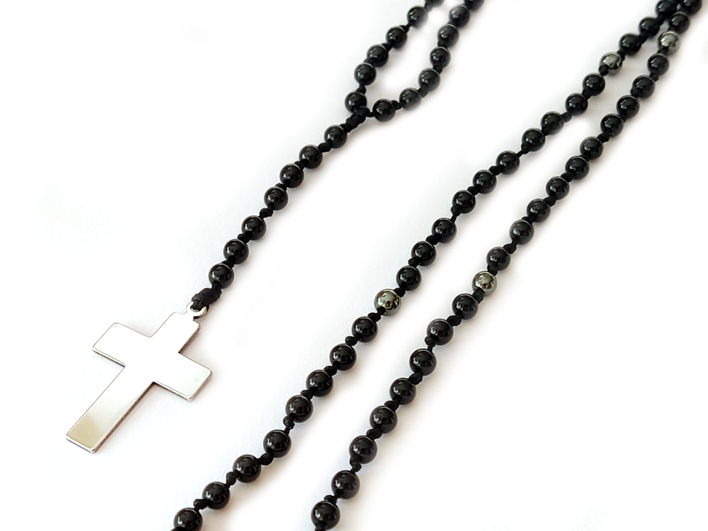 Sleek black onyx beads elegantly arranged in a rosary-style necklace, featuring a meticulously crafted cross pendant, showcasing artisanal excellence.
