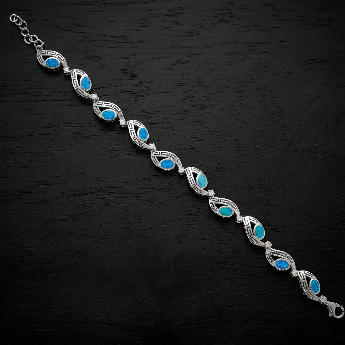 Close-up of blue opal stones and clear cubic zirconia on a Greek key silver bracelet