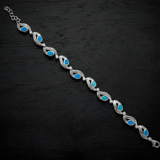 Close-up of blue opal stones and clear cubic zirconia on a Greek key silver bracelet