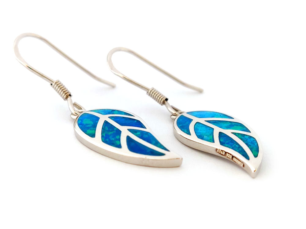 Pair of leaf-shaped silver dangle earrings with blue opal inlay on a white background
