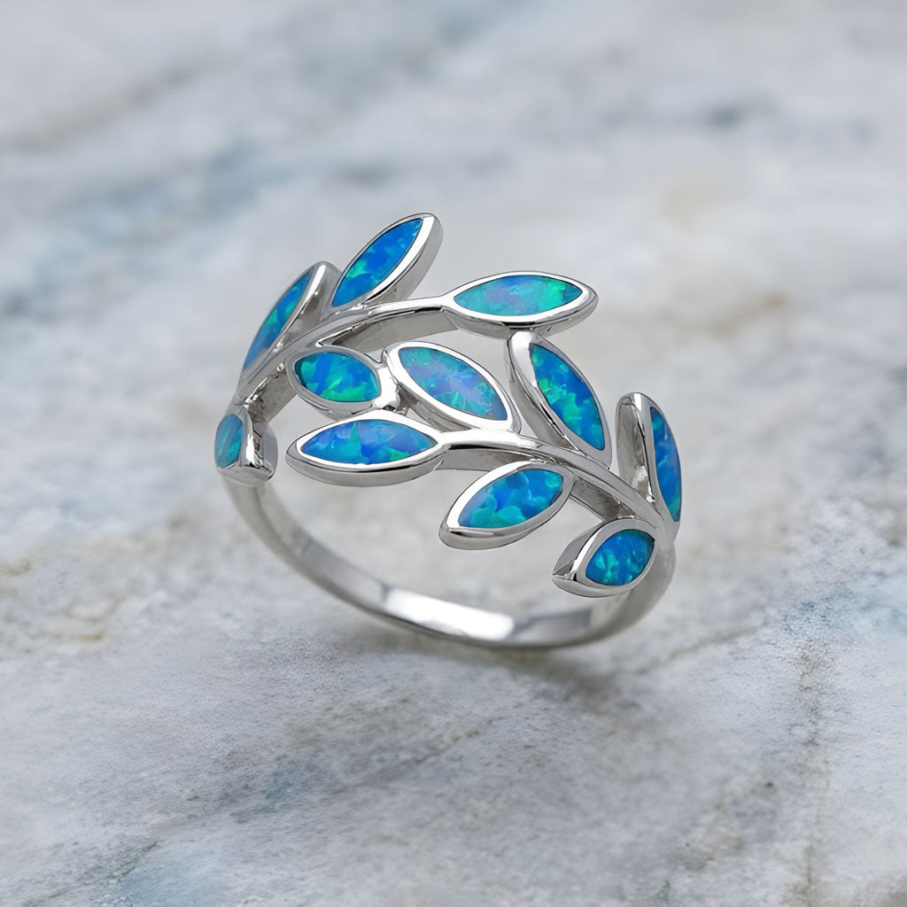 Silver ring with blue opal leaf shape stones on a marble surface