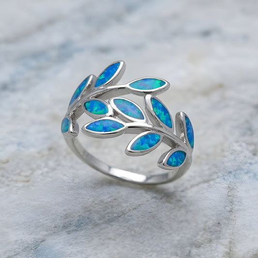 Silver ring with blue opal leaf shape stones on a marble surface