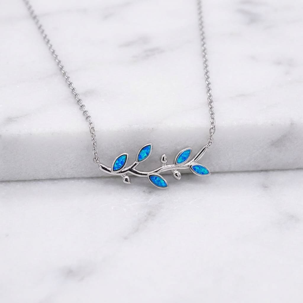Silver Greek necklace with blue opal leaves on a marble surface