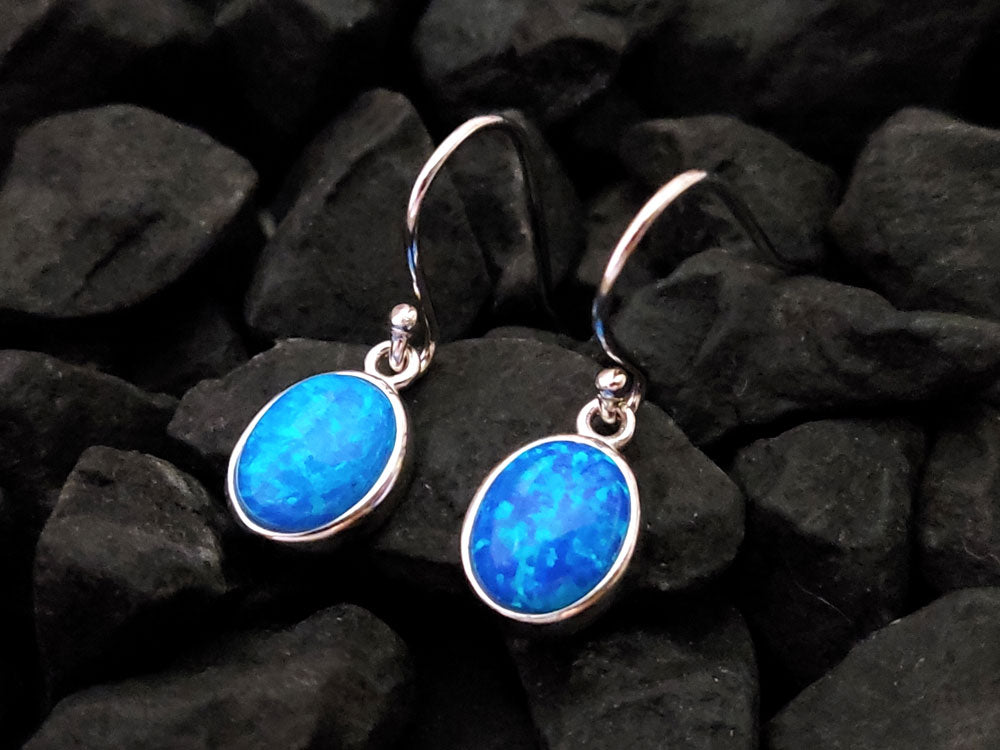 Blue opal silver earrings from Greece and oval shape blue opal stones placed on black stones.
