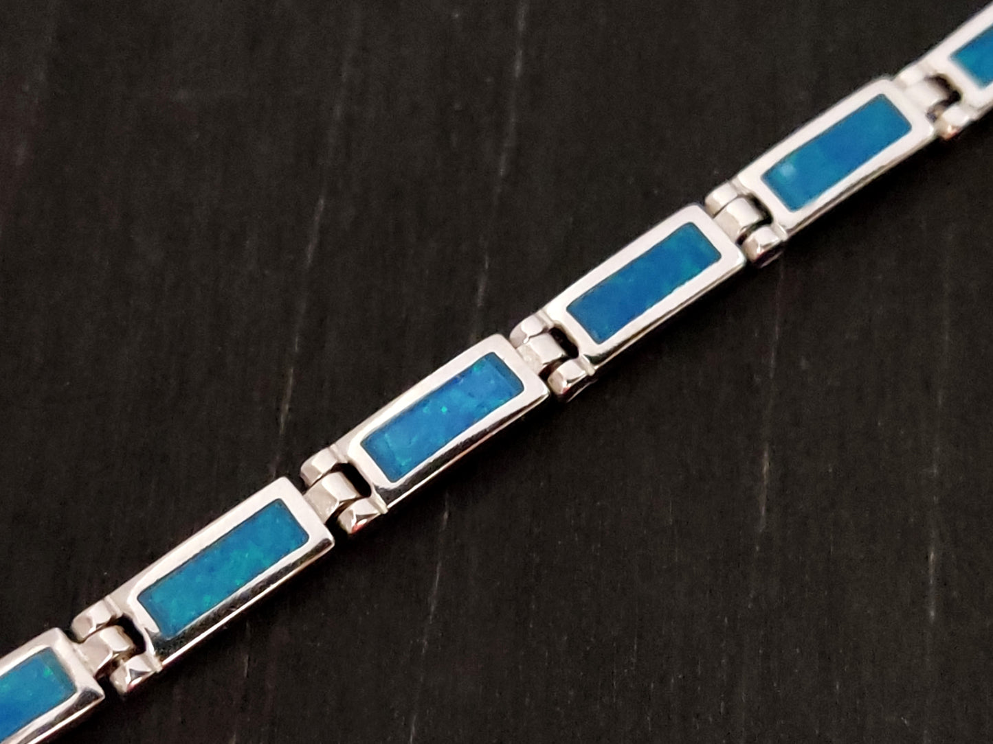 Blue opal bracelet made of silver set on black background.