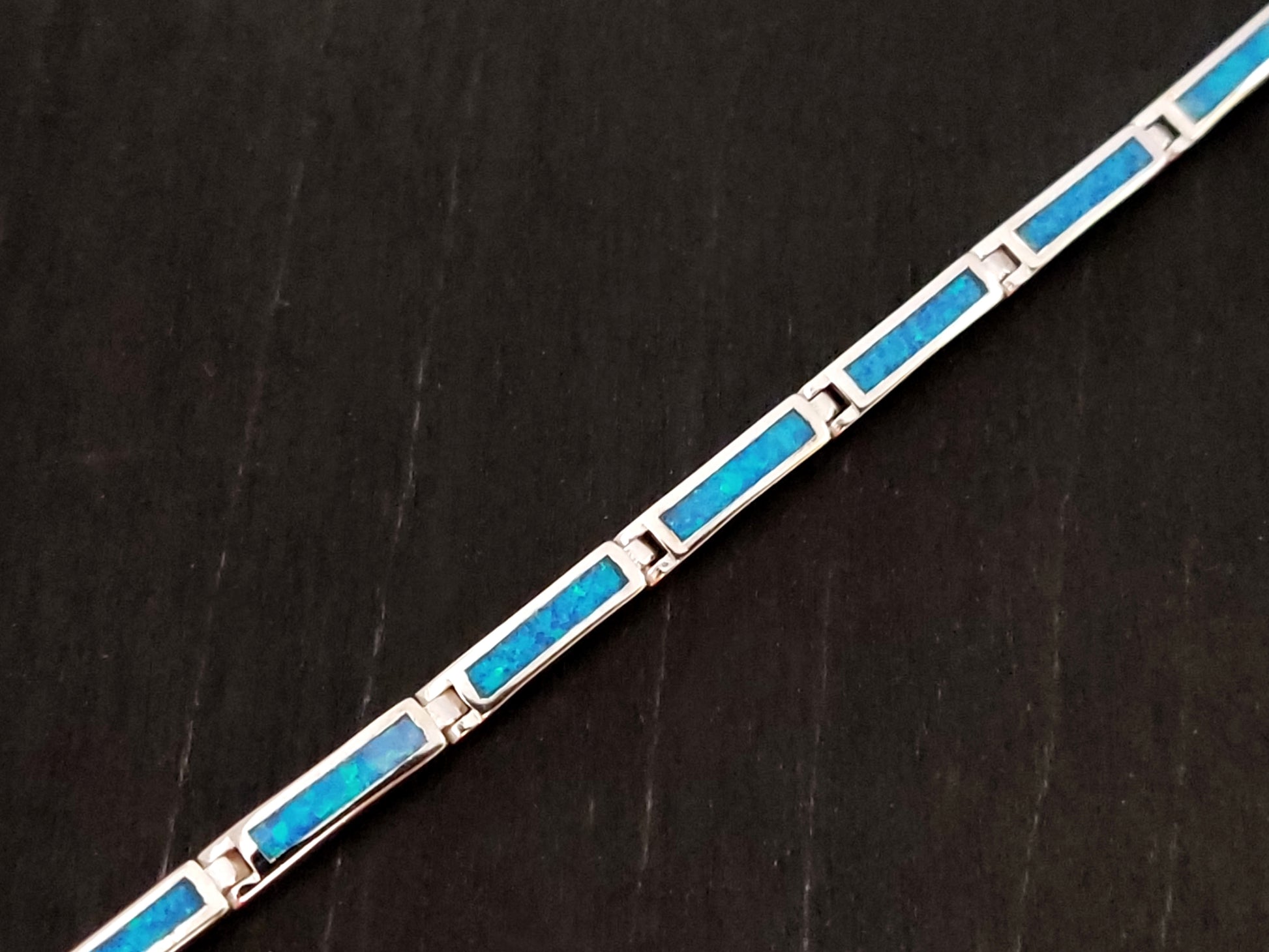 Blue opal stones bracelet made of sterling silver 925 on black background.