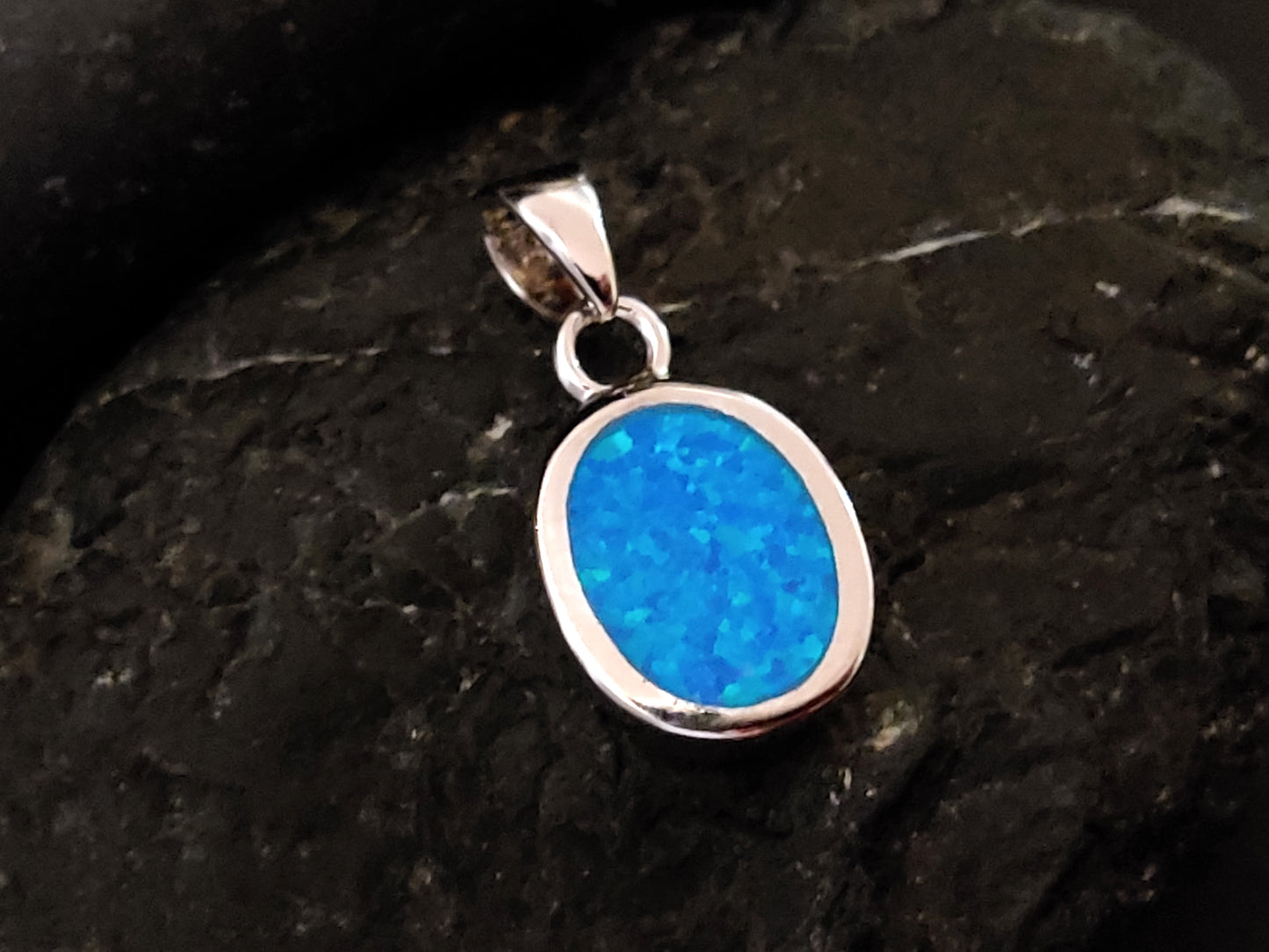 This sterling silver pendant features an enchanting oval-shaped blue opal stone, measuring 13x10mm. Inspired by Greek design, it exudes elegance and timeless beauty.