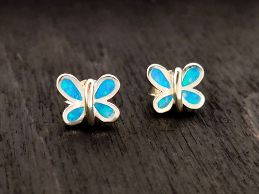 Butterfly design silver stud earrings with blue opal stones on black background measuring 9 x 7 mm.