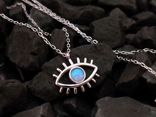 Eil eye chain pendant necklace made of Sterling Silver 925 and blue opal stone placed on black stones.