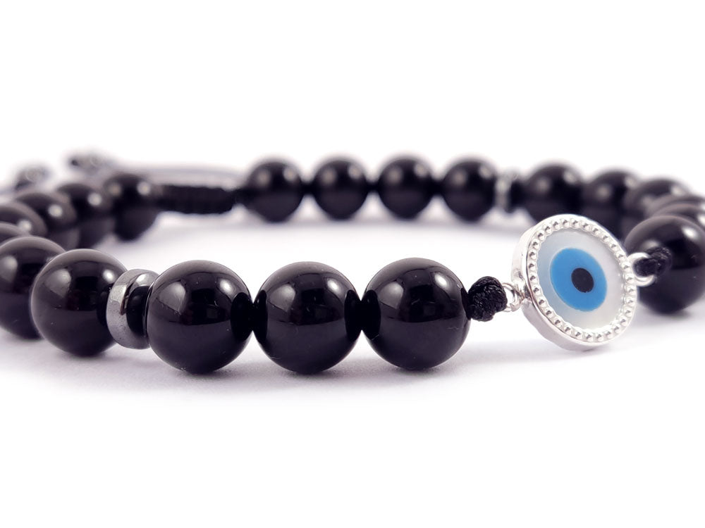 A handmade bracelet featuring Sterling Silver 925 with a 10mm (0.39 inches) Mother of Pearl Evil Eye centerpiece, complemented by 8mm natural onyx black stones. The bracelet is designed with a slide clasp for adjustable fit. Made in Greece with a Hallmark 925 stamp, offering free worldwide shipping.