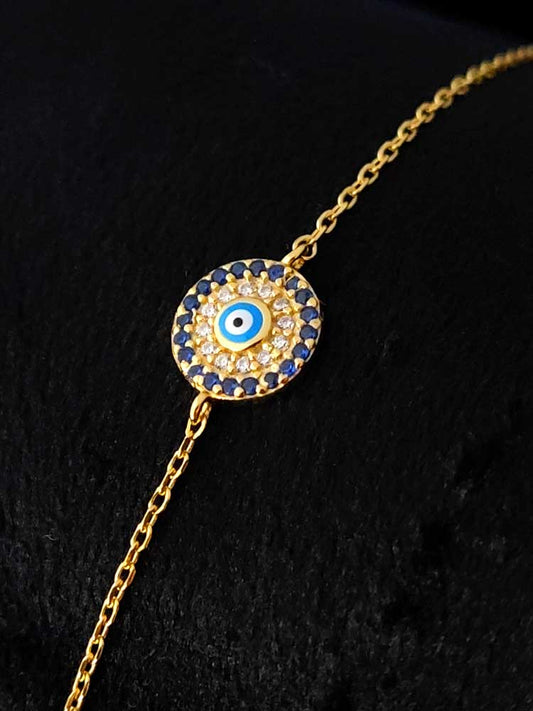 Close-up of a gold-plated sterling silver Evil Eye Nazar bracelet with dark blue crystals, 9 mm pendant, adjustable 16–19 cm chain.
