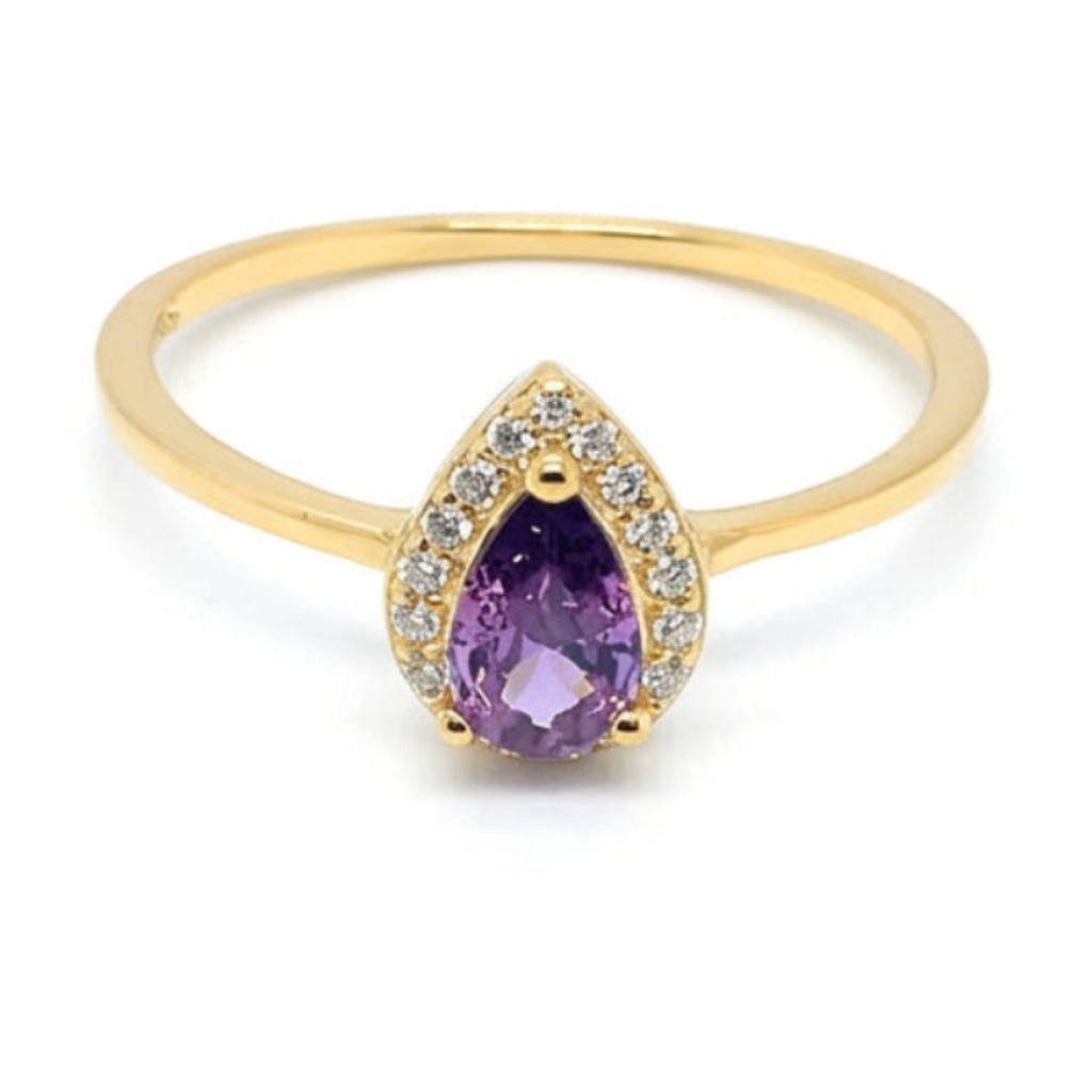 A gold ring featuring a teardrop-shaped purple amethyst color crystal center stone surrounded by small clear accent stones, set on a plain white background.