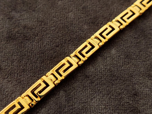 Greek Key silver bracelet from Greece with gold plated finish measuring 5mm width on gray velvet.