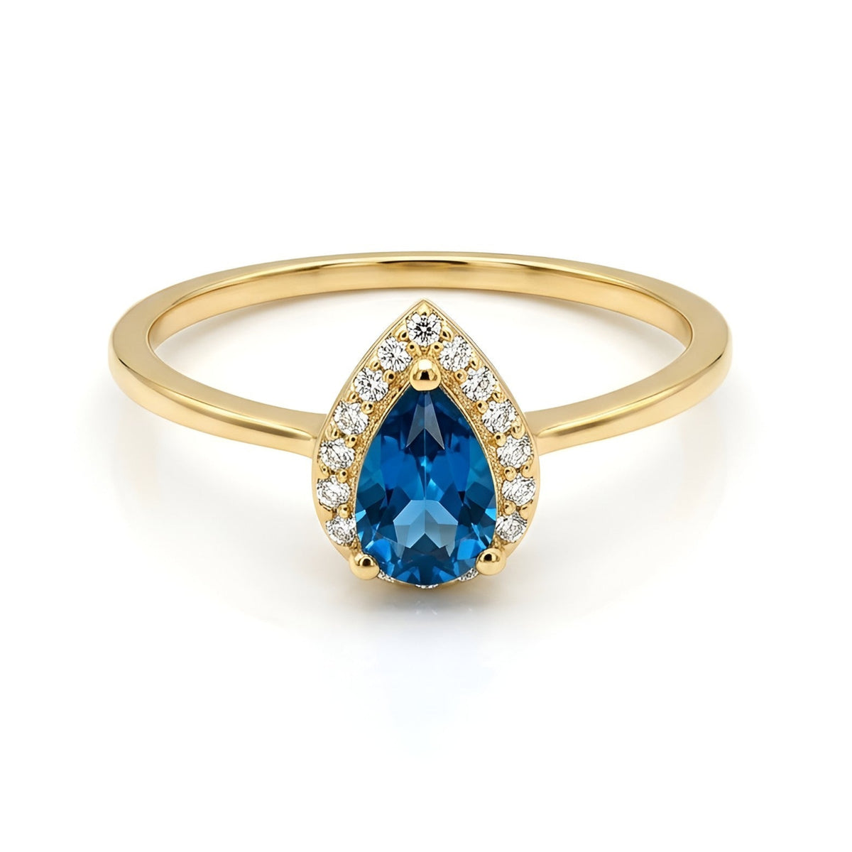 A gold ring featuring a teardrop-shaped blue gemstone surrounded by small clear stones, set against a plain white background.