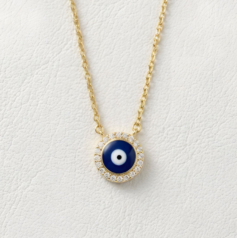 Gold plated silver necklace with a blue evil eye pendant on a white background