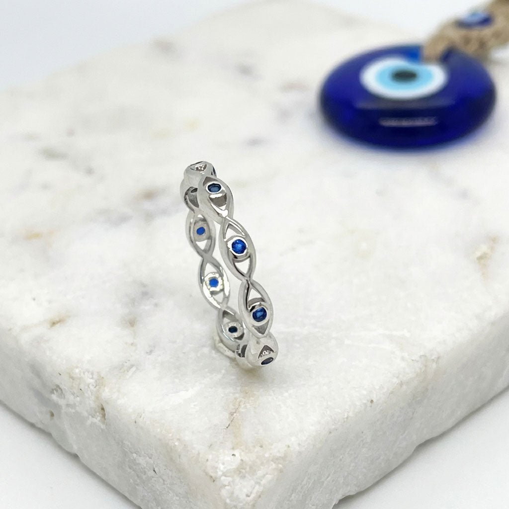 Evil Eye silver ring with blue stones on a white stone surface
