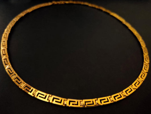 Greek silver necklace with gold plated finish on black background.