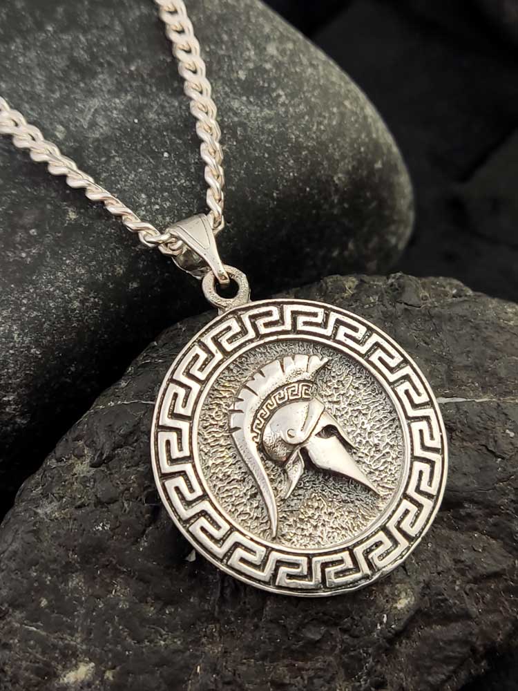 Sterling silver 925 Greek helmet pendant placed on a soft fabric background, emphasizing the fine craftsmanship.

