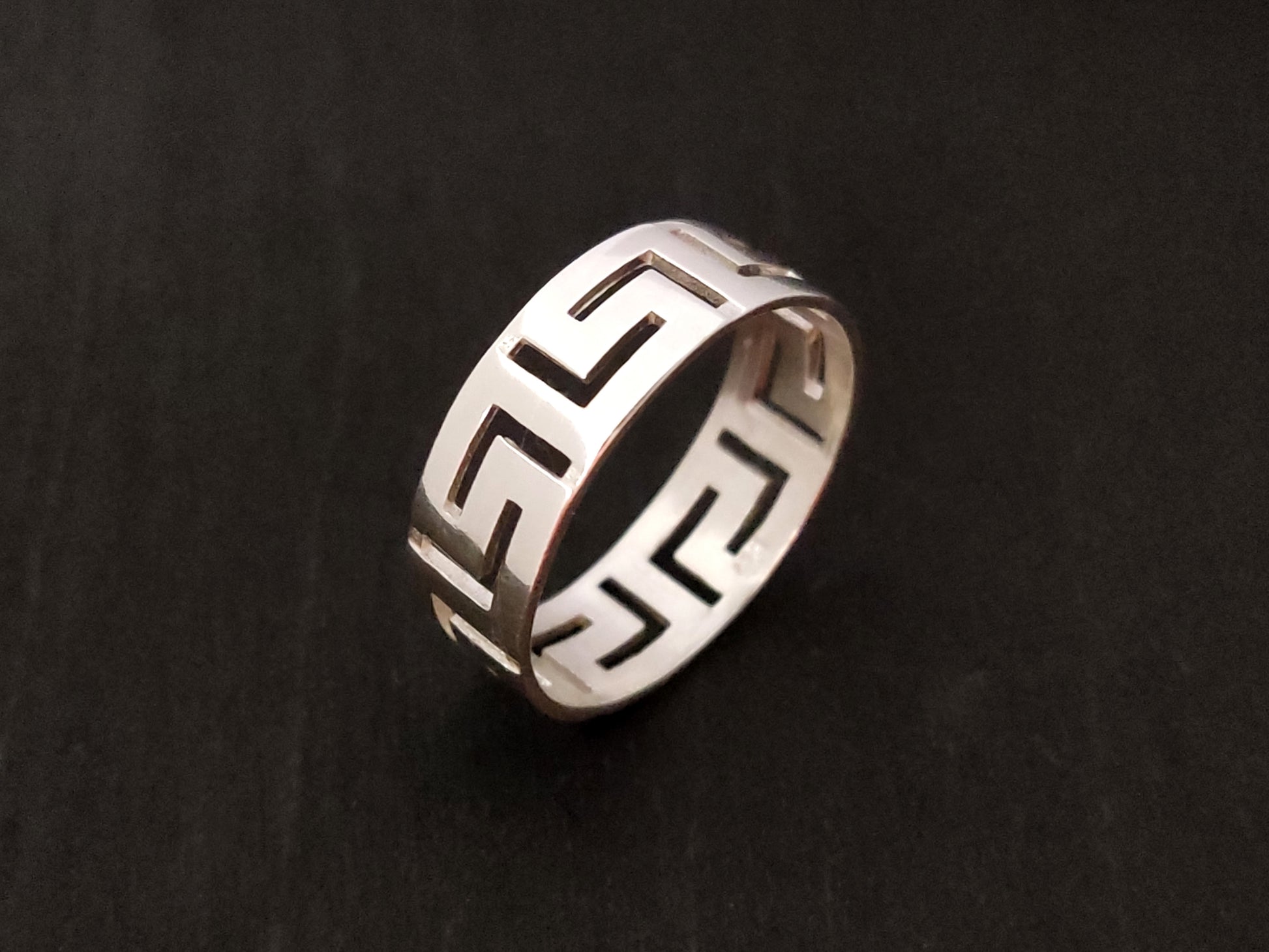 Greek Key silver ring on black background.