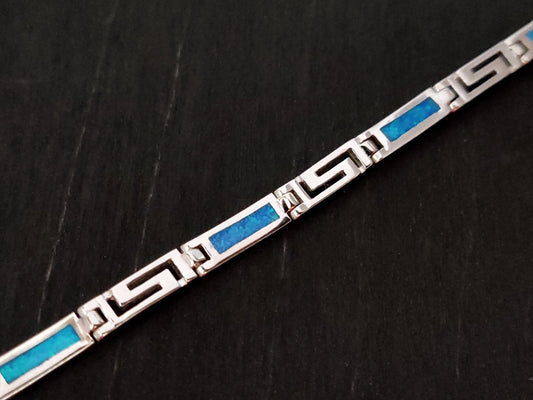 Greek Key bracelet made of sterling silver 925 and blue opal stones measuring 4mm width, placed on black background.