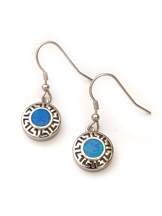 Greek key silver dangle earrings in round shape with blue opal stones in the middle placed on white background.
