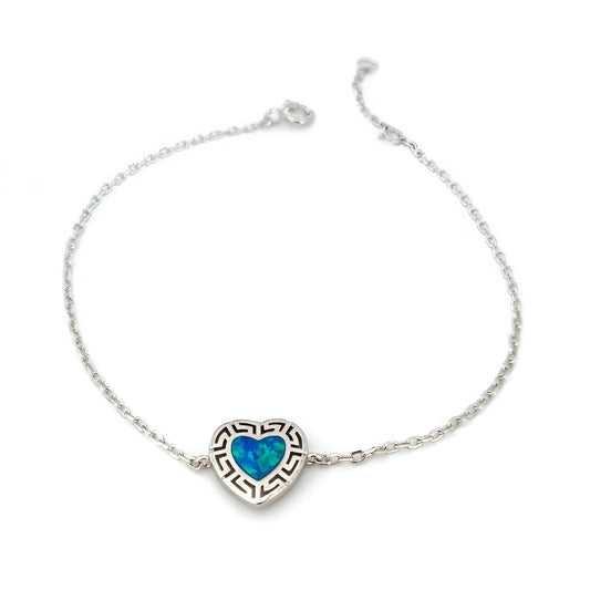 A delicate sterling silver chain bracelet featuring a heart-shaped pendant with a blue opal inlay and a Greek key border design, set against a plain white background.