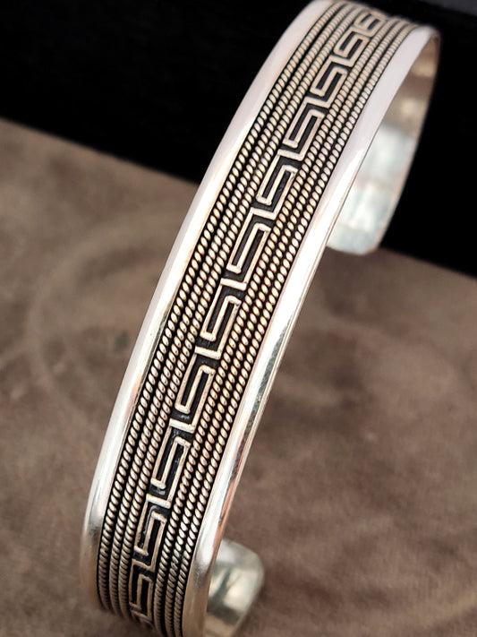 Greek Key cuff made of sterling silver 925 on gray velvet and black background.