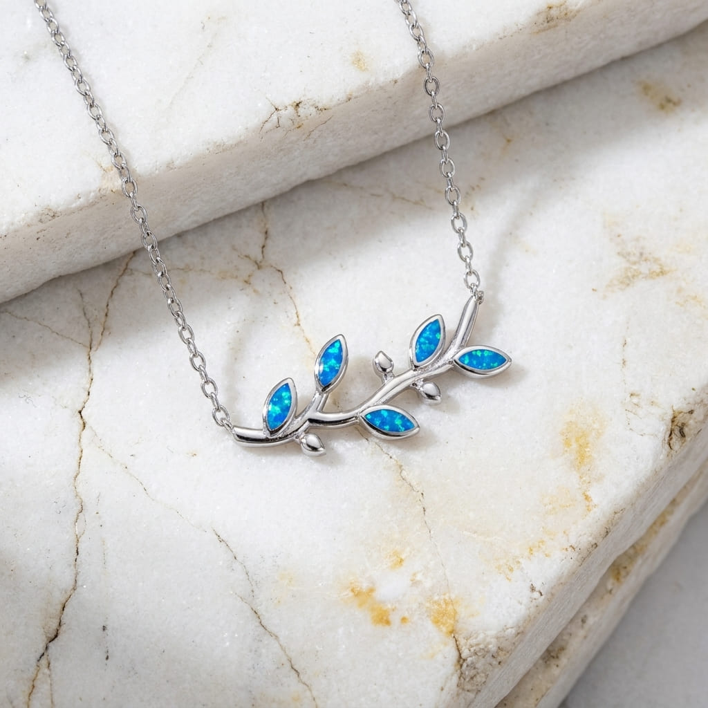 Silver Greek necklace with blue opal leaves on a marble surface