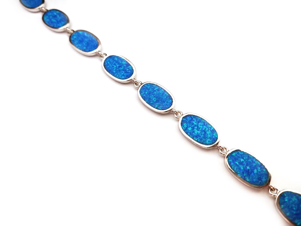 "Elegant sterling silver bracelet featuring vibrant blue opal stones, handcrafted in Greece."
