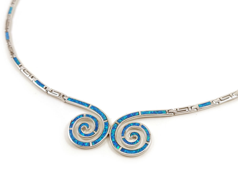 Greek silver necklace with double spiral design and blue opal stones placed on white background.