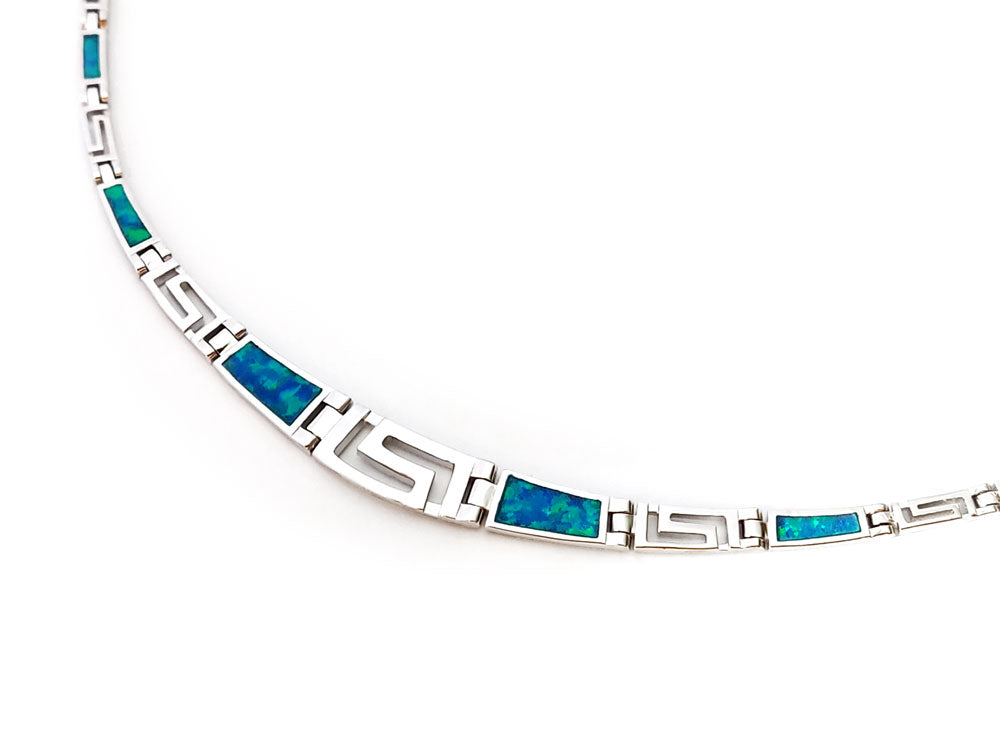 Close-up view of a Greek Key silver necklace with blue opal stones and a lovely gradual design.
