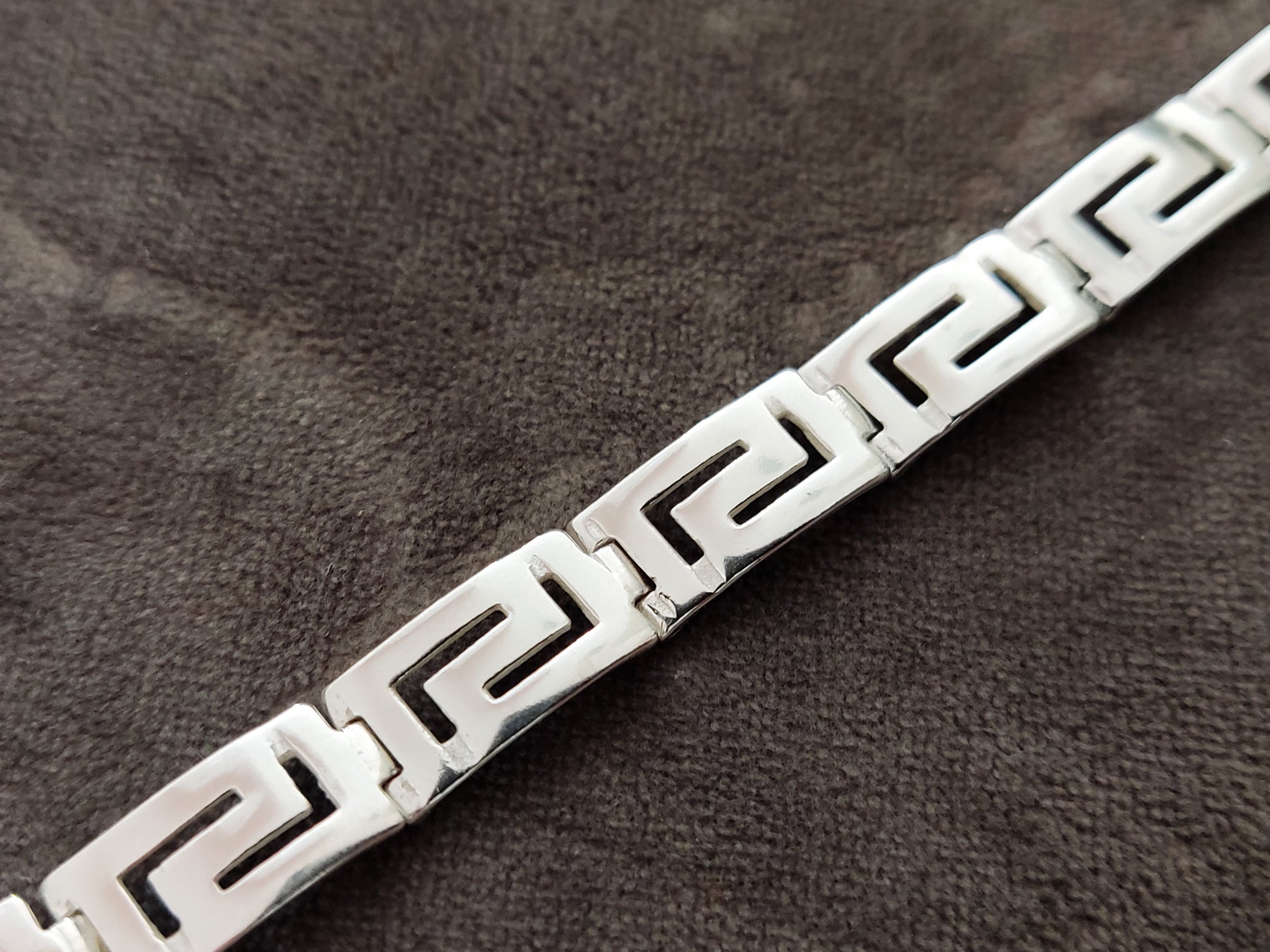 Greek key bracelet for men and women made of sterling silver 925 measuring 9mm width on gray velvet background.