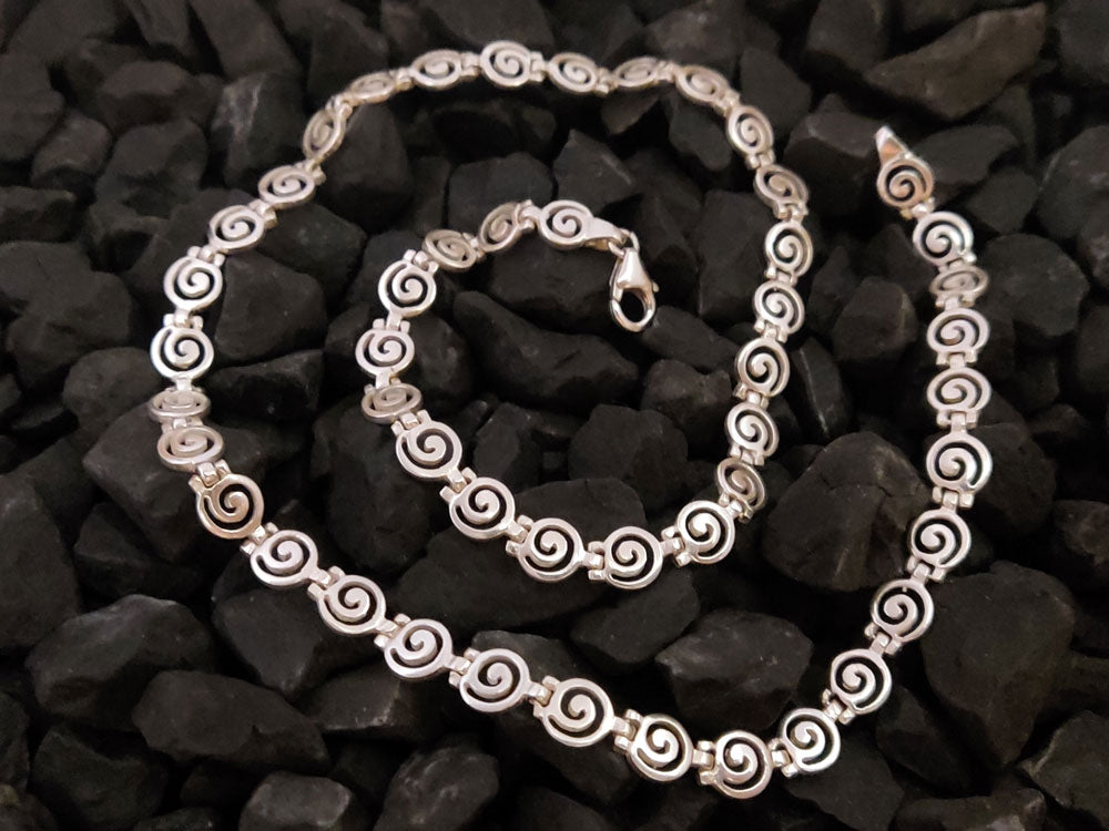 Spiral silver necklace made of Sterling Silver 925 measuring 7mm in width placed on black stones.