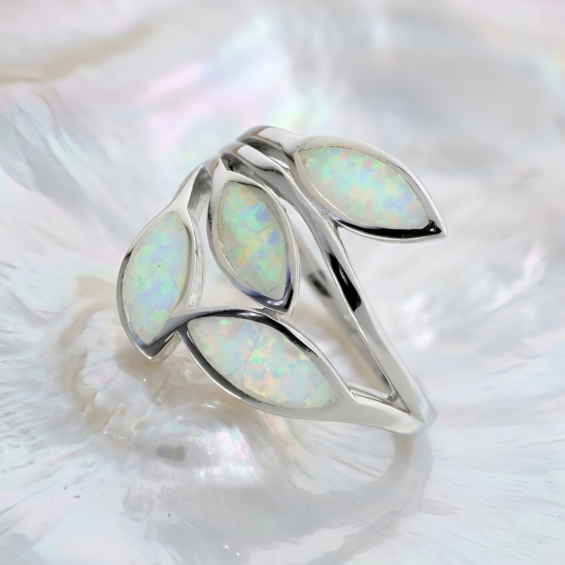 A silver Greek ring featuring five marquise-cut white opal inlays, displayed on a textured white shell.
