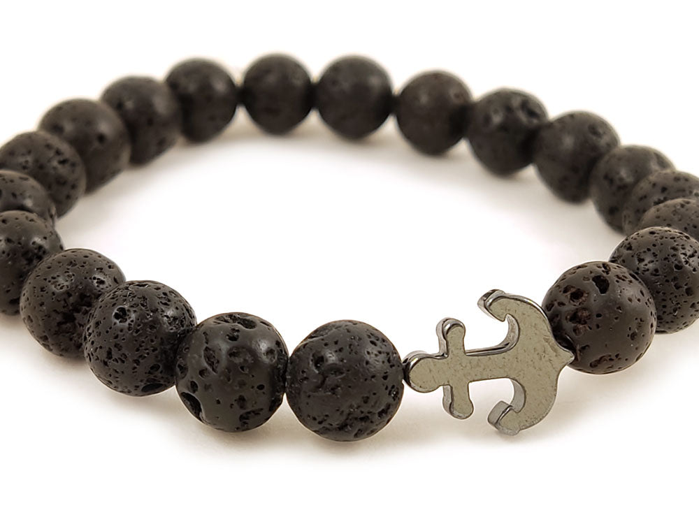 Black lava stones bracelet from Greece and anchor shape hematite placed on white background.