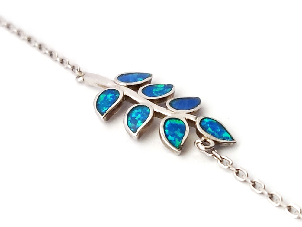 "Close-up of 11mm wide 925 silver bracelet featuring vivid blue opal stones and olive leaf motifs, adjustable length."
