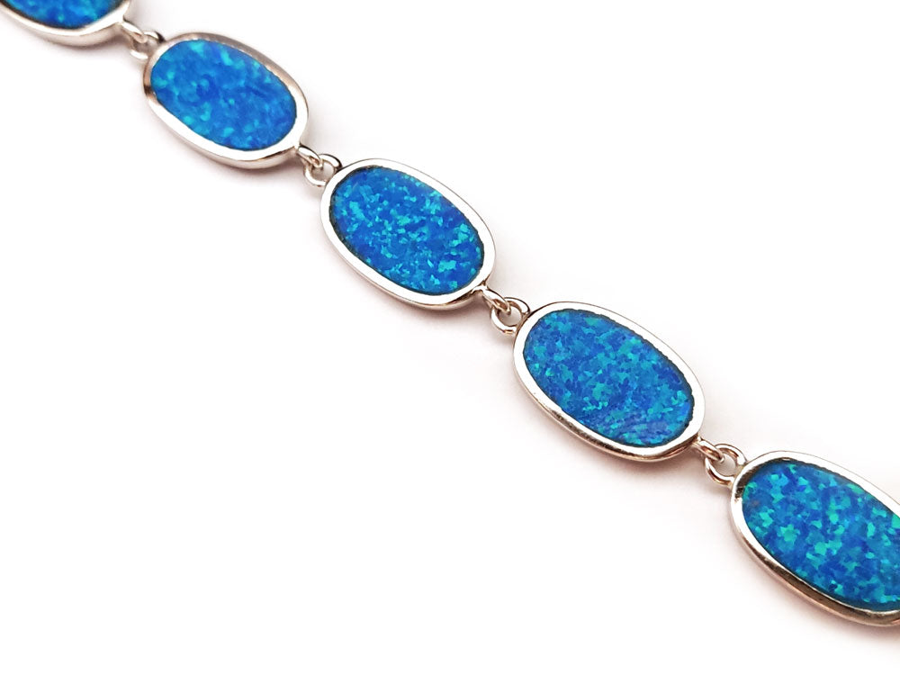 "Adjustable 925 silver bracelet with 11mm blue opal stones, a perfect accessory for any outfit."
