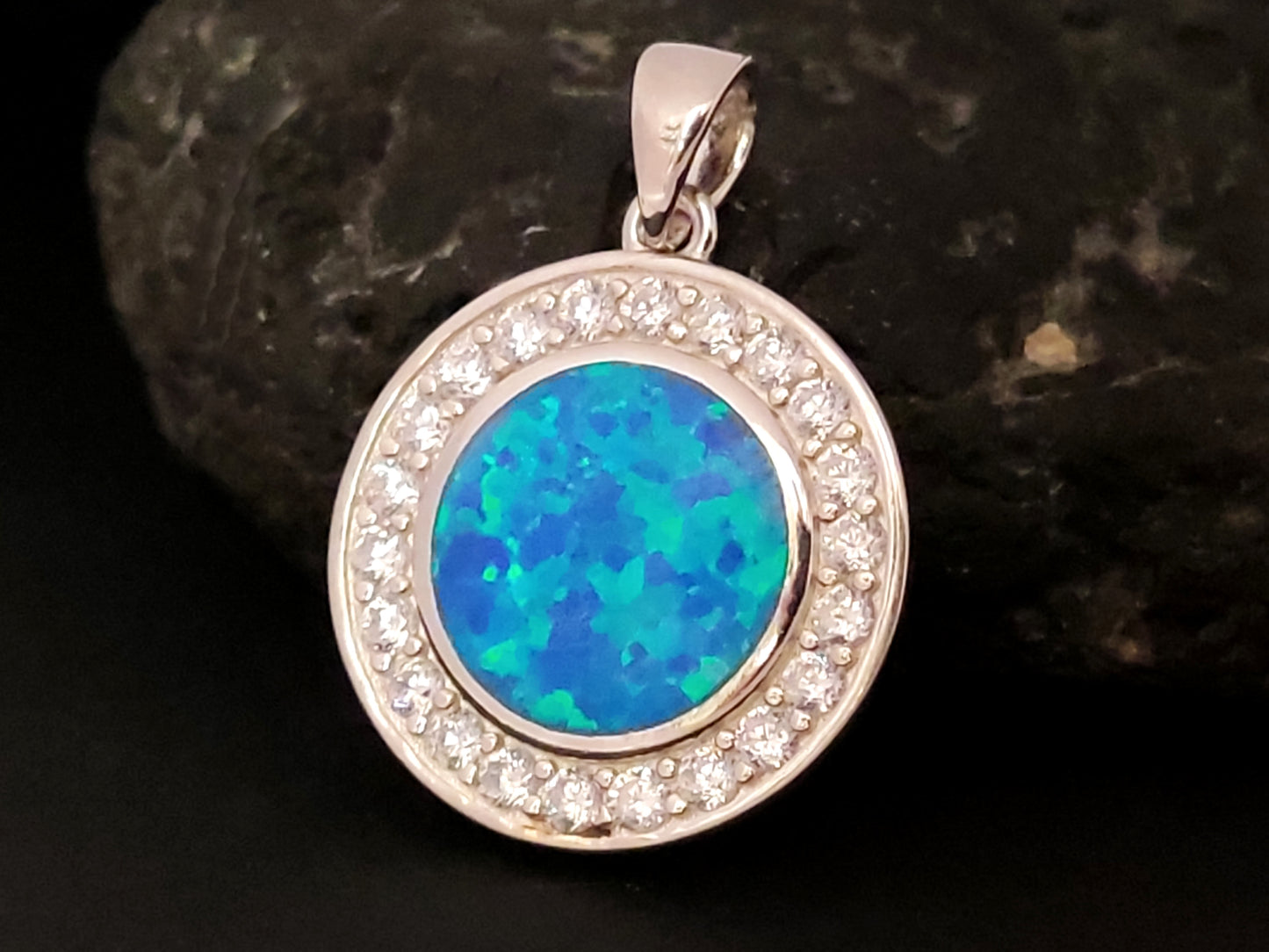 Silver pendant from Greece in round shape with blue opal and transparent crystals.