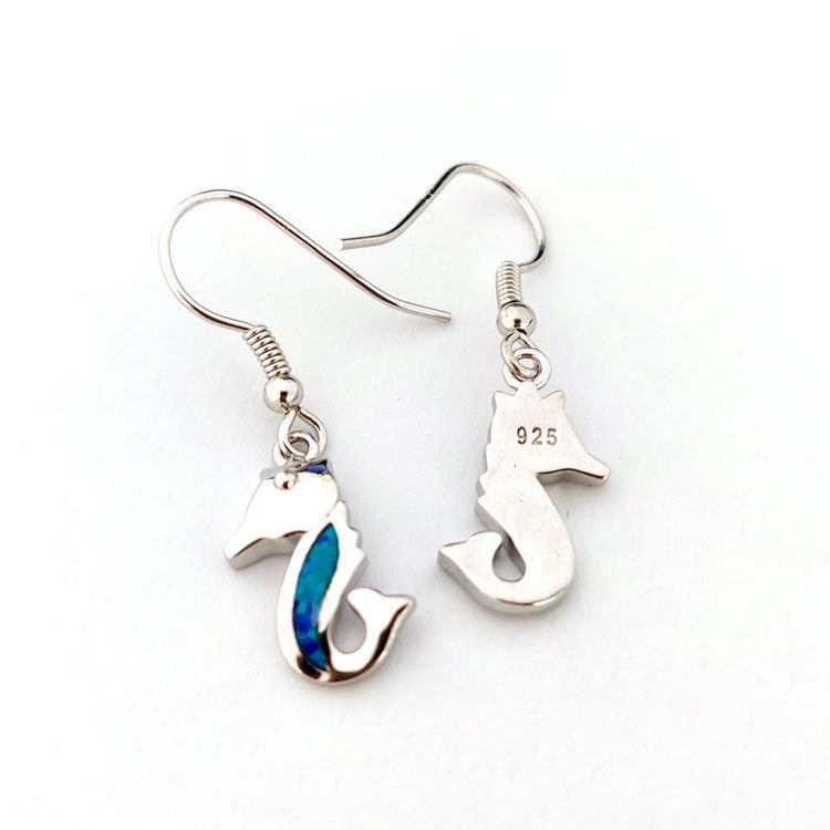 Silver seahorse-shaped earrings with a blue opal accent on a white background