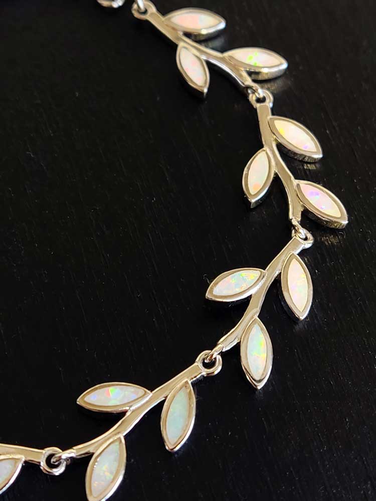 Close up photo of a Greek silver bracelet with white opal leaf shape stones.