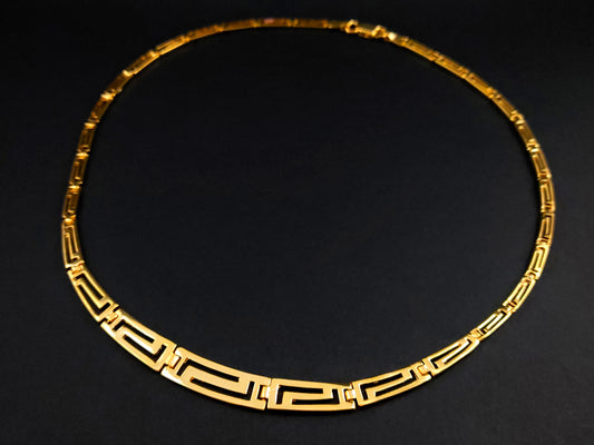 Greek Key silver necklace with gold plated finish in a gradual pattern on black background.