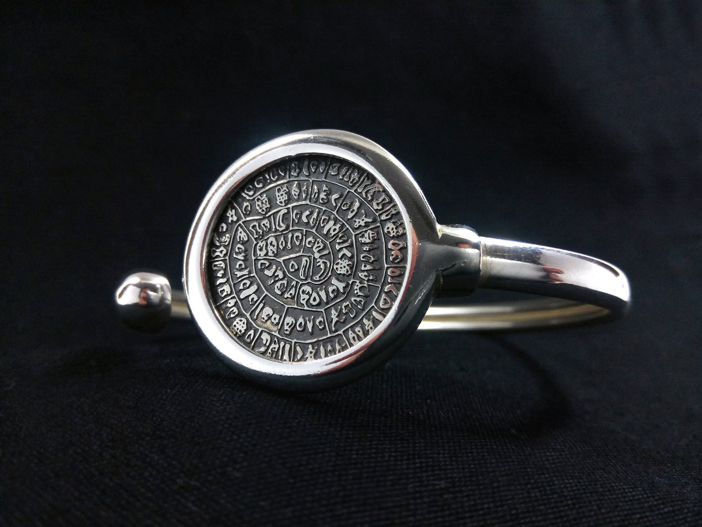 A silver cuff bracelet with the Phaistos Disc