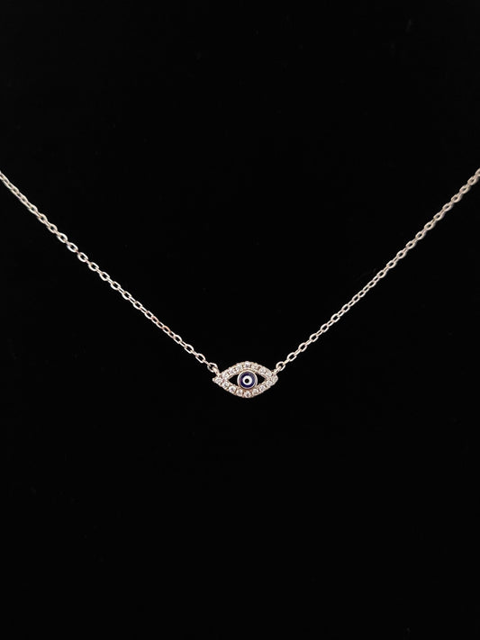 Silver evil eye fine necklace with black background.